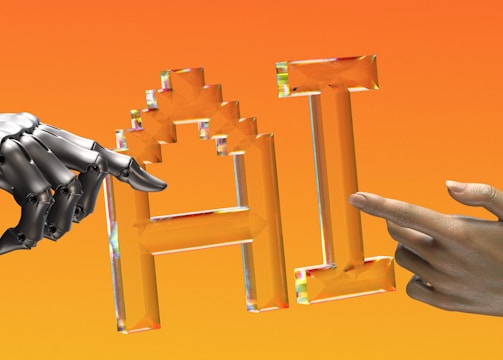 A metallic robotic hand and a human hand point towards each other at the center. Between them, there is a stylized, crystal-like representation of the letters 'AI'. The background is a gradient of orange shades.